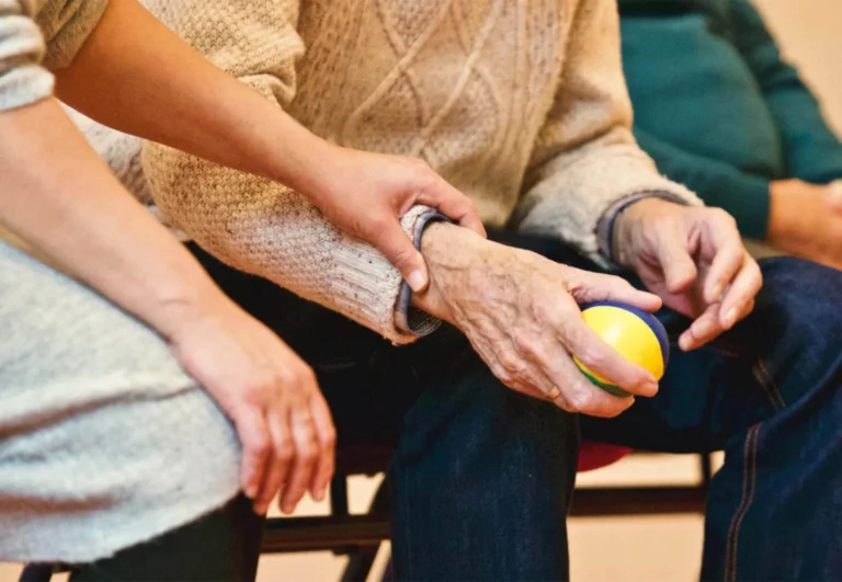 Carer holding an older person's hands during a gentle exercise