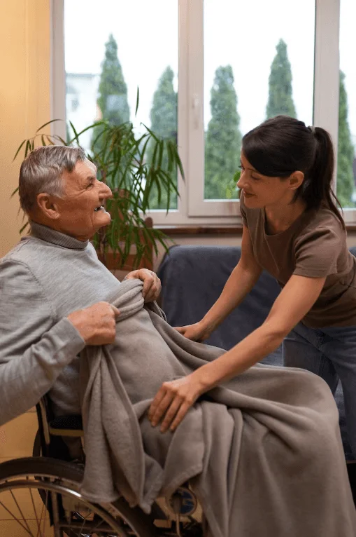 Carer helping an older man with a blanket