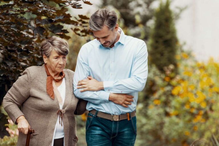 Carer and older woman walking outdoors together