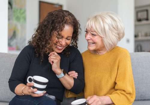 Two women laughing together over a cup of tea