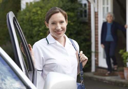 Smiling carer standing beside a car before a home visit