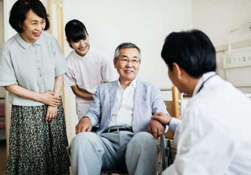 Carer talking with an older man and his family